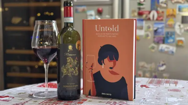 Un bicchiere di vino rosso Nebbiolo d'Alba, una bottiglia e un libro "Untold" sul vino. Le caratteristiche del Nebbiolo sono un viaggio affascinante.