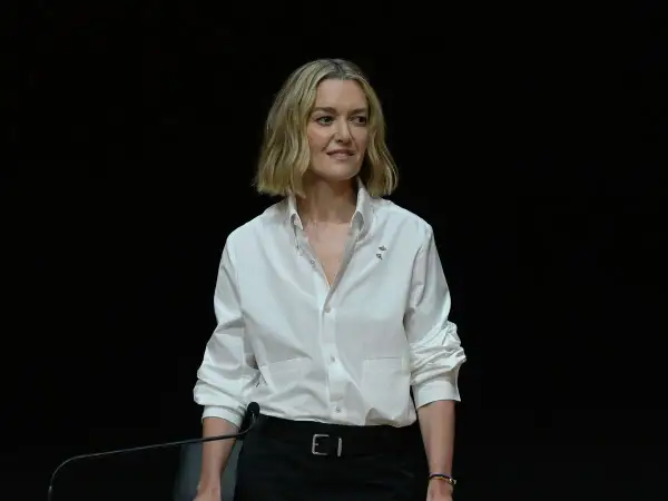 Marta Ortega Pérez, con una camisa blanca y un micrófono, sonríe ante la cámara.