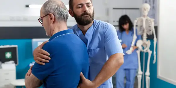 Fizjoterapeuta pomaga pacjentowi z bólem pleców w nocy i nad ranem.