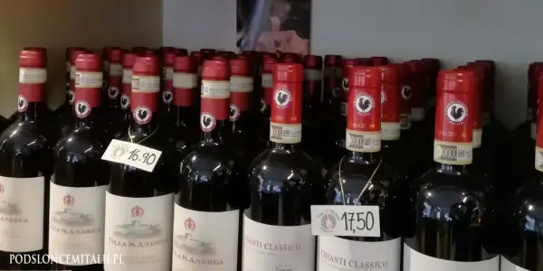 Rzędy butelek wina z kogutem na etykiecie. Na niektórych widnieją ceny: 16,90 i 17,50.