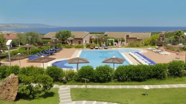 Villaggio con piscina e lettini, vista mare. Una **cala rosa** al **mattinata** ideale per rilassarsi.