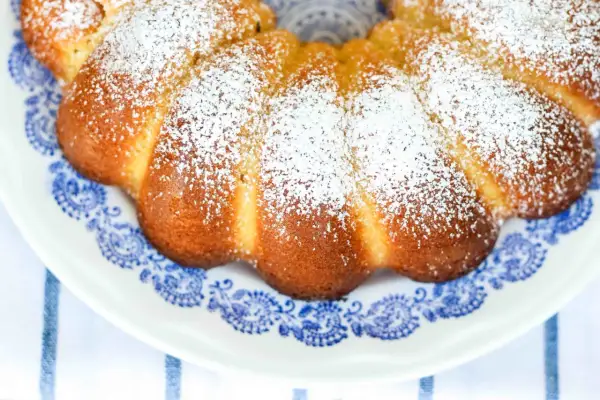 Deliziosa torta al latte caldo, cosparsa di zucchero a velo, su un piatto con decori blu.