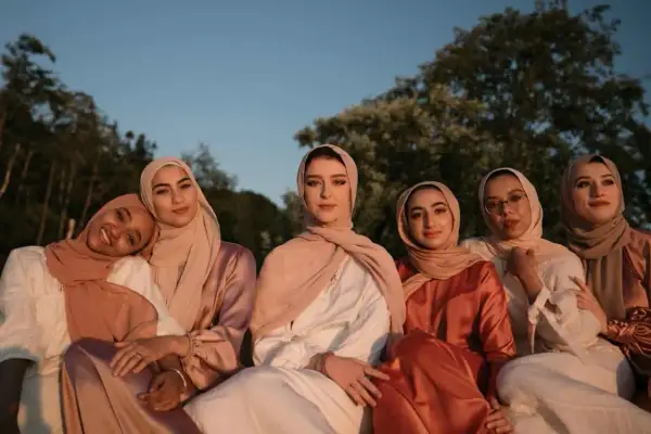 Seis mujeres con hiyabs posan juntas. El tejido modal se arruga suavemente en sus vestidos, creando un efecto elegante bajo la luz del atardecer.