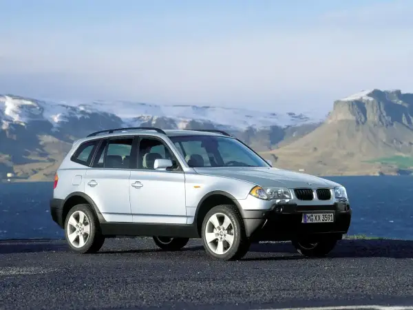 Srebrny BMW X3 E83 na tle gór i morza.