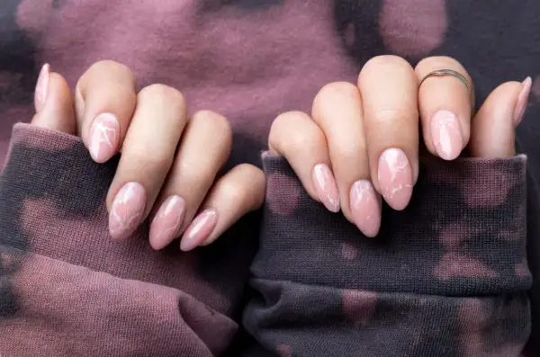Delikatne, różowe paznokcie z białym wzorem marmuru. Inspiracja z "1001 pomysłów na paznokcie" na subtelny manicure.
