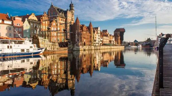 Gdańska starówka z żaglowcem i statkiem wycieczkowym, idealne instagramowe miejsca Gdańsk. Odbicia budynków w wodzie tworzą magiczny widok.