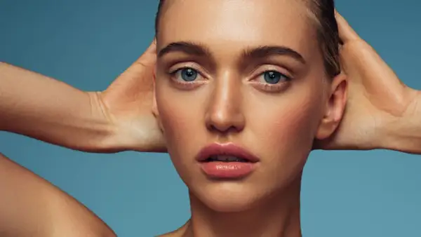 Rostro de mujer con piel radiante y labios jugosos. El retinol ayuda a renovar la piel, revelando su luminosidad natural.
