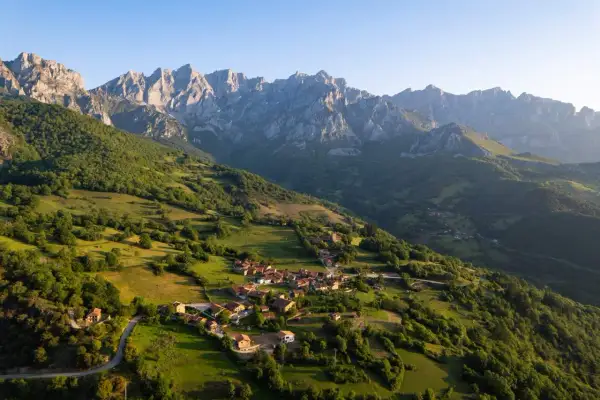 Un pueblo anidado en verdes colinas bajo los imponentes Picos de Europa. Descubre curiosidades de los Picos de Europa en este paisaje idílico.
