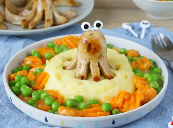 Ein lustiges gesundes Abendessen für Kinder: Würstchen-Oktopus auf Kartoffelbrei mit Erbsen und Karotten.