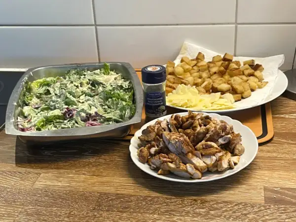 Förberedelser för ett fantastiskt ceasarsallad recept: krispig sallad, stekt kyckling, krutonger och parmesan.