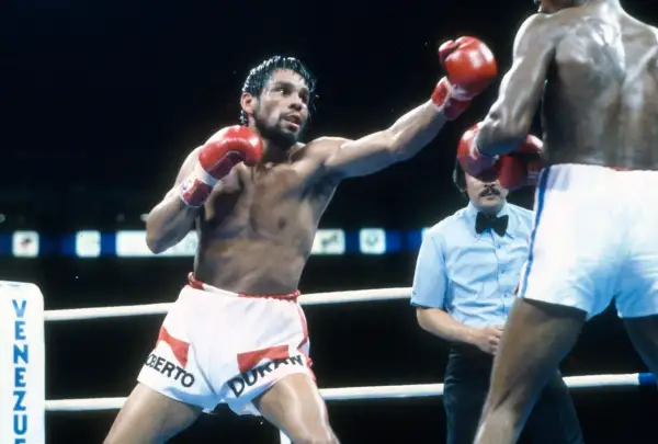 Roberto Duran, the legendary boxer, throws a punch in the ring. His red gloves are raised, ready for action.