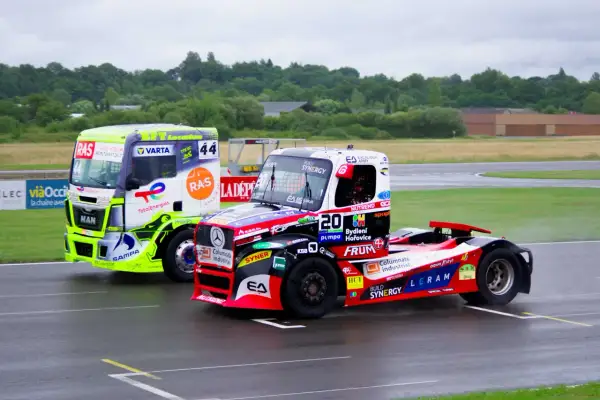 Deux camions de course s'affrontent sur le circuit. Le camion vert vif et le camion rouge et noir sont prêts pour le grand prix camion Nogaro.