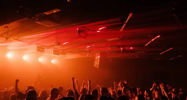 Folla in delirio in una delle tante discoteche techno, con luci laser rosse che illuminano la scena.