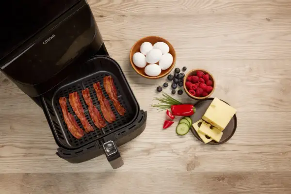 Krispigt bacon i airfryer, redo för en god frukost med ägg, bär och ost.