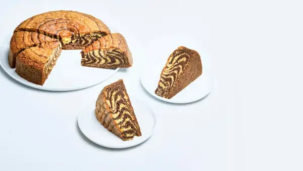 En saftig tigerkaka med vackra mönster, perfekt för ett enkelt tigerkaka recept. Två skivor serveras på vita fat.