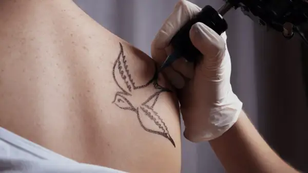Tatuaż jaskółki, symbol wolności i nadziei, powstaje na skórze.