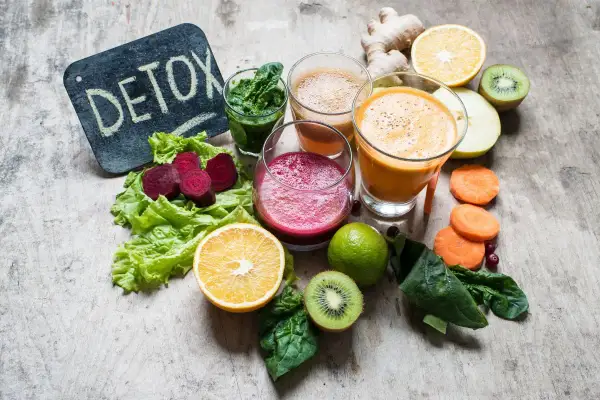 Kolorowe soki i warzywa na drewnianym tle. Tabliczka z napisem "DETOX" sugeruje, że te składniki pomagają w walce z tym, co zakwasza organizm.