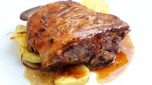 Ternasco asado jugoso y dorado, servido sobre patatas. ¡La mejor opción donde comer ternasco en Zaragoza!