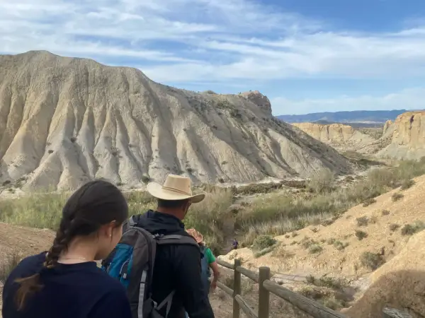 Senderos del desierto de Almería, con formaciones rocosas erosionadas y vegetación escasa. Un grupo de excursionistas se adentra en el paisaje.