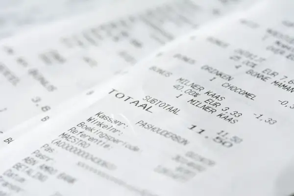 Zbliżenie na paragony z widocznymi nazwami produktów, cenami i sumą całkowitą.