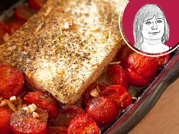 Ein Block Feta mit Kräutern und Gewürzen, umgeben von gebackenen Kirschtomaten. Perfekt für ein schnelles Gericht mit Nudeln mit Feta.