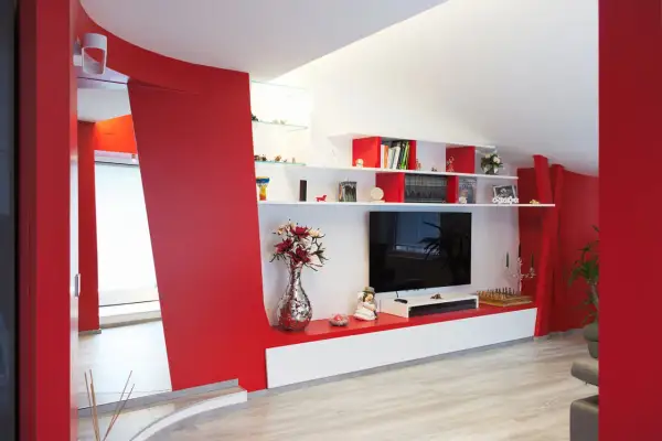 Pareti soggiorno rosso e grigio con mobile TV, libreria e decorazioni.