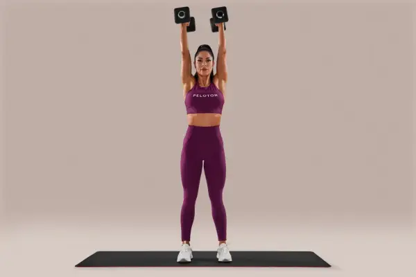 Woman performing arm-toning exercises for females with weights, holding dumbbells overhead.