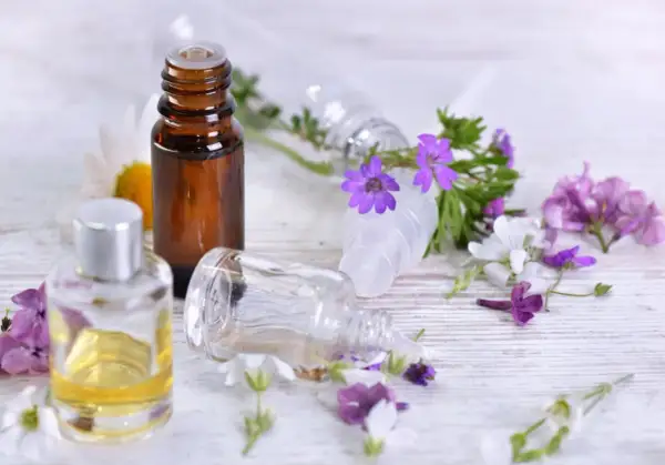 Aromaterapia: amol na co pomaga? Butelki z olejkami i kwiaty sugerują relaks i ukojenie.