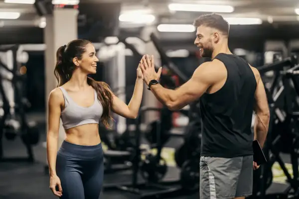Coppia si dà il cinque in palestra, ispirata da schede palestra con immagini per un allenamento efficace.