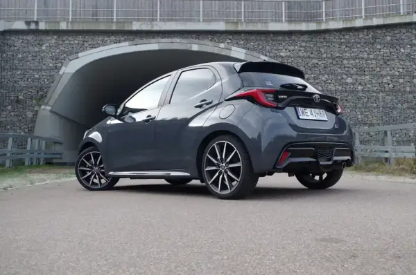 Szary Toyota Yaris Hybrid z czarnym spoilerem i felgami stoi przed tunelem.