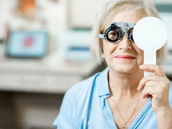 Starsza kobieta z soczewkami próbnymi na oczach, badanie wzroku w celu diagnozy zaburzeń widzenia ICD 10.