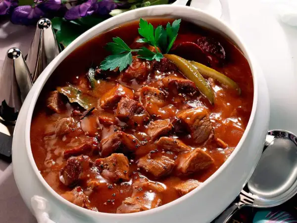 Herzhaftes Pfefferpotthast Rezept in einer Schüssel, garniert mit Petersilie und Gewürzgurken. Ein Klassiker der westfälischen Küche.