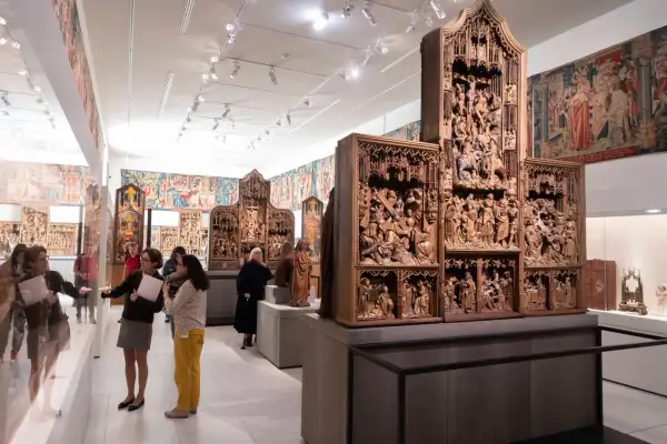 Besucher bestaunen im Cluny Museum detailreiche Holzschnitzereien und Wandteppiche.