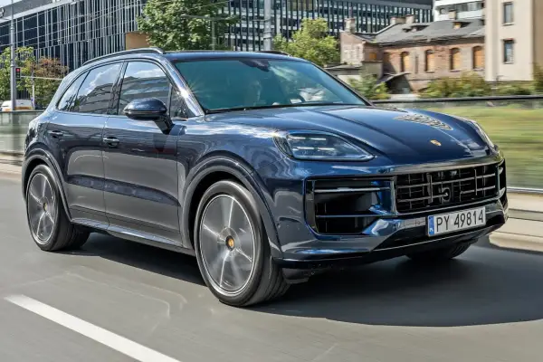 Ciemnoniebieski Porsche Cayenne jedzie po mieście. Sprawdź aktualną porsche cayenne cena.