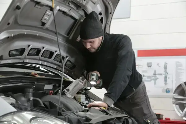 Mechanik z latarką bada silnik Renault, szukając przyczyny błędu DTC P0300.