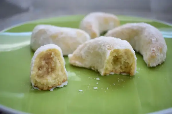 Petits gâteaux en forme de croissant, saupoudrés de sucre glace. Ces délices ressemblent à des cornes de gazelle, prêts à être dégustés.