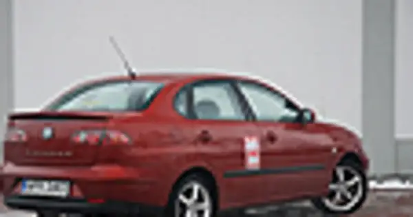 Czerwony Seat Cordoba z naklejką na drzwiach, zaparkowany na zewnątrz.