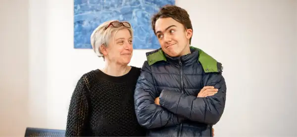 Un sorriso complice tra una donna e un ragazzo autistico, un momento di connessione e comprensione.