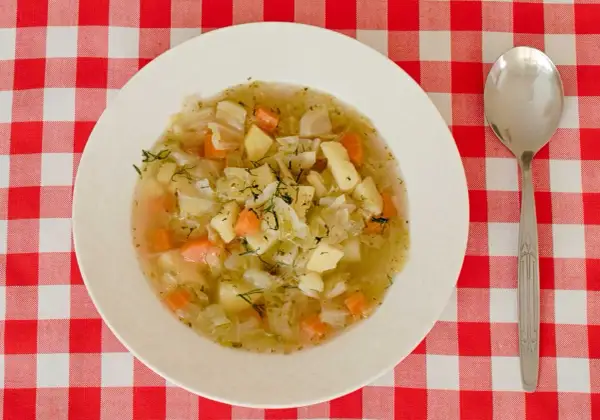 Aromaticzna zupa ze słodkiej kapusty z ziemniakami i marchewką, posypana świeżym koperkiem.