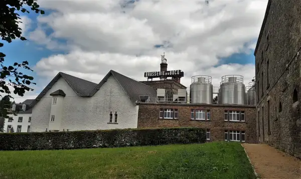 Edificio della Brasserie du Bocq con serbatoi in acciaio inox e un cielo nuvoloso.
