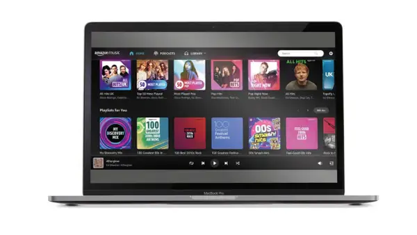 Laptop z interfejsem Amazon Music Unlimited. Widoczne playlisty: "All Hits UK", "Pop Right Now", "My Discovery Mix" i "Feel-Good 00s Hits".