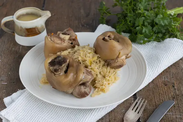 Drei deftige Eisbeine auf Sauerkraut, serviert mit Soße. Ein klassisches Eisbein Rezept für Genießer.