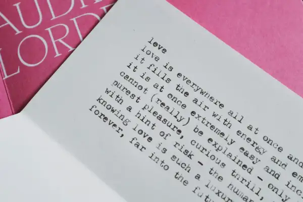Piękny wiersz o miłości i tęsknocie, z tekstem "love is everywhere" na białej kartce, obok różowej okładki z napisem "AUDRE LORDE".
