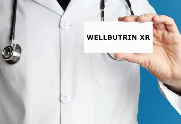 Lekarz w białym kitlu prezentuje kartkę z napisem WELLBUTRIN XR.