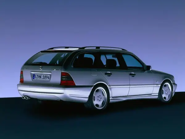 Srebrny Mercedes C klasa 2000 kombi z felgami AMG, widziany z tyłu, na tle niebieskiego gradientu.