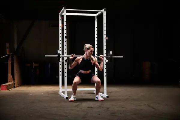 Kvinna utför squats med stång i ett gym.