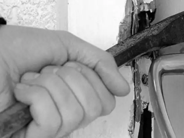 Mano con cincel forzando una puerta, una imagen que evoca la problemática de los okupas en España.
