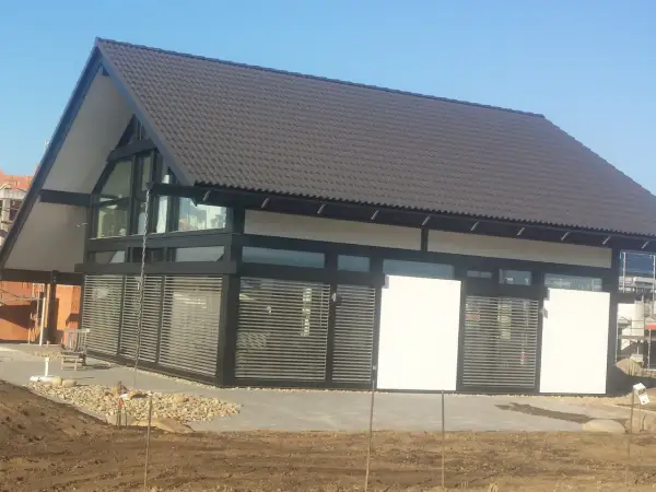 Nowoczesny dom z dużymi oknami dźwiękoszczelnymi, zadaszeniem i żaluzjami.