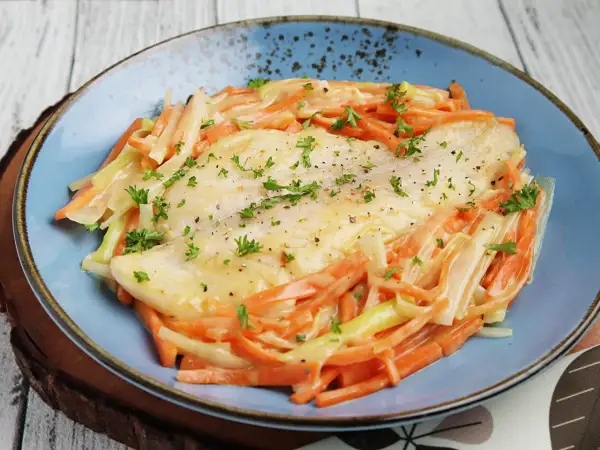 Ein zartes Rotbarschfilet mit einer cremigen Senfsauce, umgeben von julienniertem Gemüse.