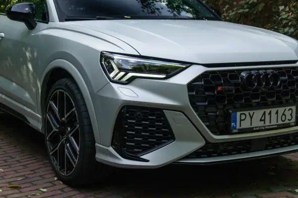 Srebrne Audi RS Q3 z czarnymi felgami i agresywnym grillem, gotowe do jazdy po warszawskich ulicach.